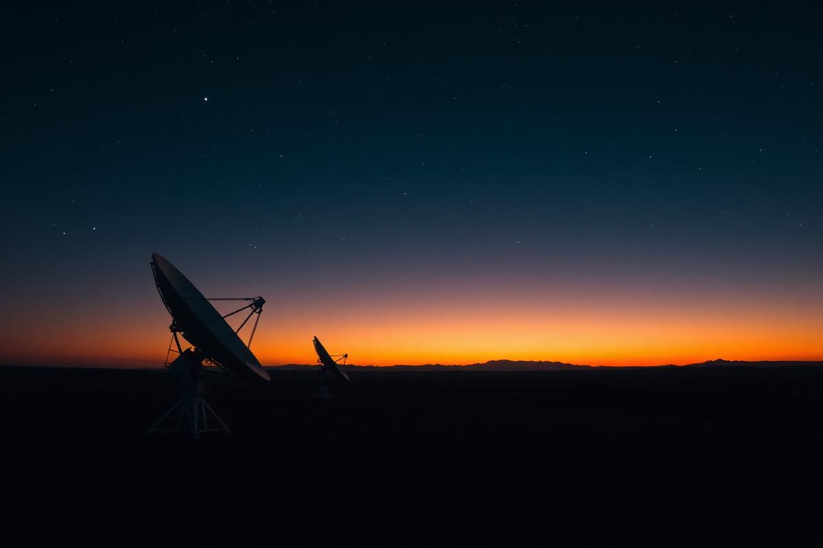 Satellite ground station dishes silhouetted at twilight